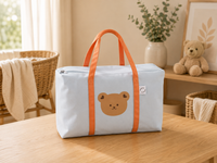 Sac à langer cabas, motif ours, bleu, posé dans un intérieur clair aux tons naturels