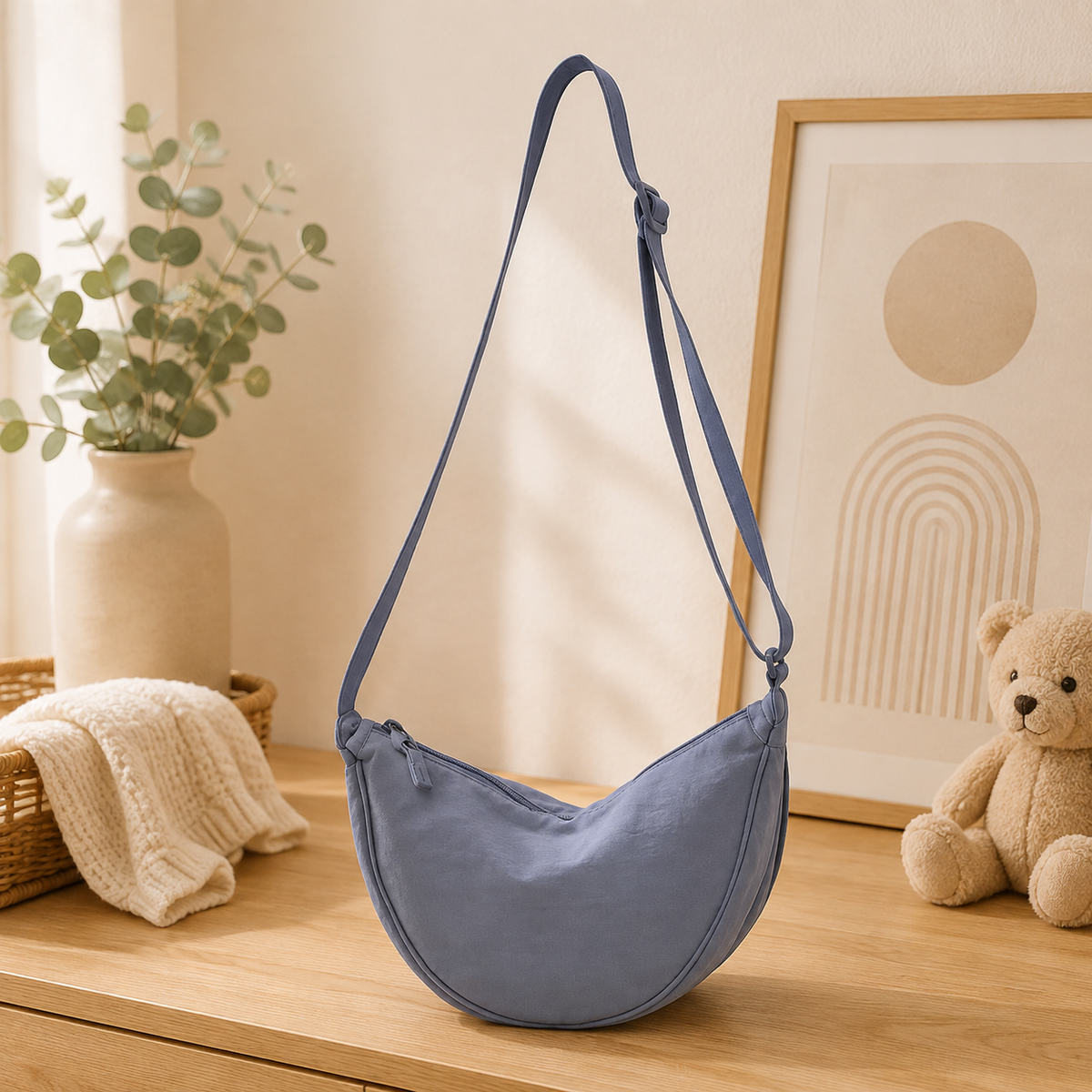 Sac à langer bandoulière, en toile, bleu, posé dans un intérieur clair aux tons naturels
