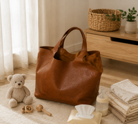 Sac à langer cabas en simili cuir marron, style rétro, posé dans un intérieur clair aux tons naturels