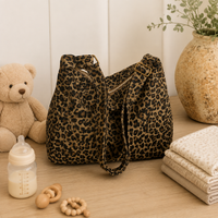 Sac à langer bandoulière, kaki, 3 coloris, posé dans un intérieur clair aux tons naturels