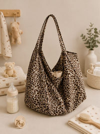 Sac à langer bandoulière, léopard, posé dans un intérieur clair aux tons naturels