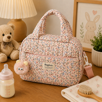 Sac à langer isotherme compact, trois motifs, posé dans un intérieur clair aux tons naturels