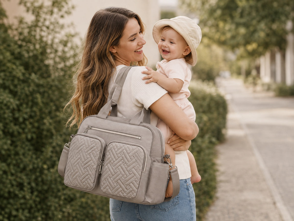 Une mère porte son enfant, son sac à langer à l'épaule Image